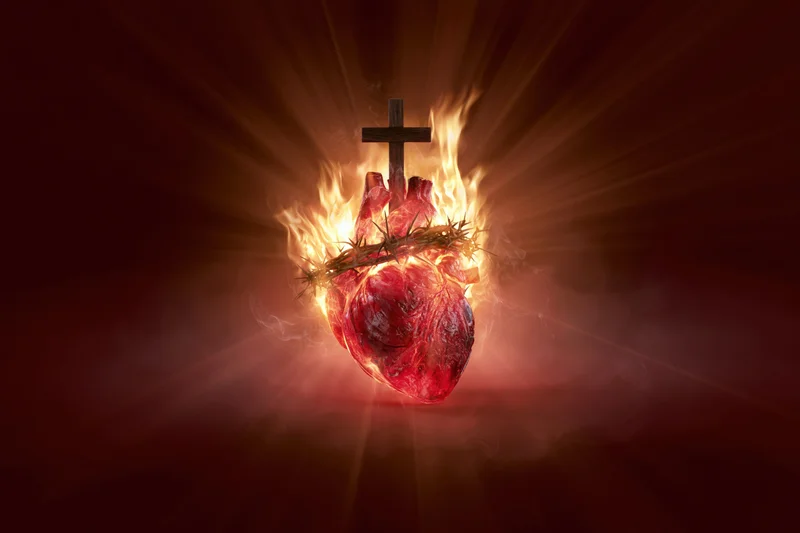 Glowing red heart wrapped in crown of thorns with cross and flames against dark background