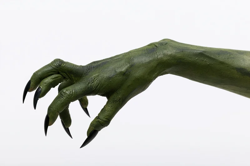 Green-painted monster hand with sharp claws extended against white background