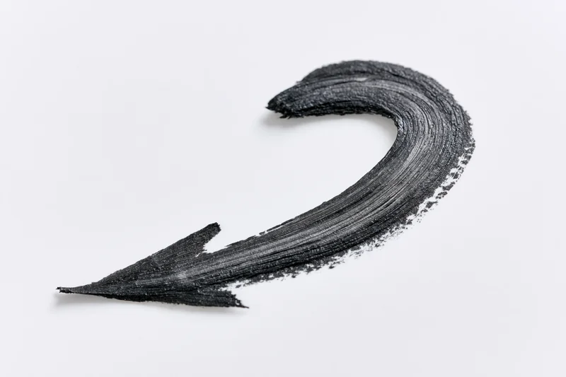 Curved black brushstroke arrow pointing downward left on white background