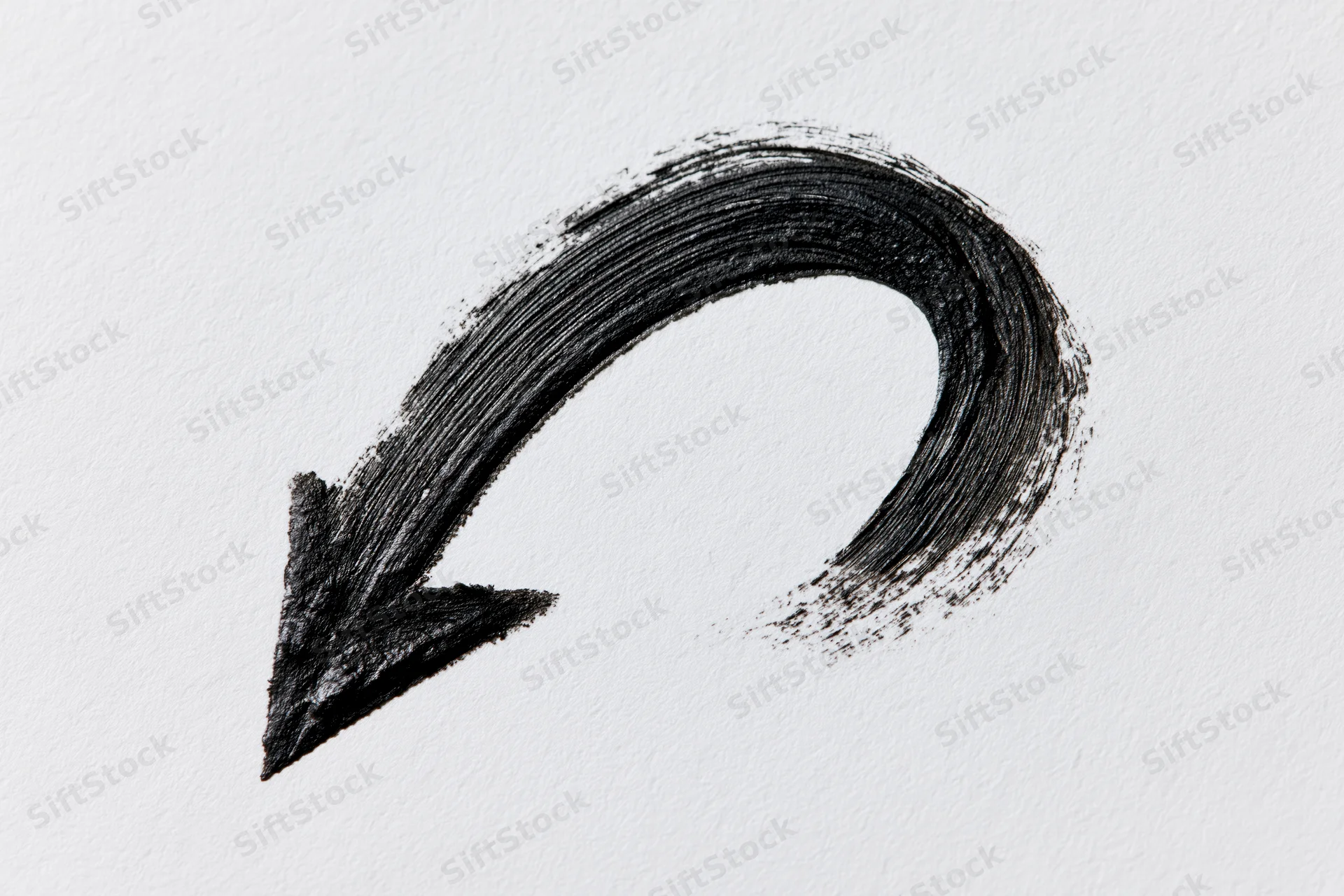 Hand-drawn curved arrow pointing downward-left on white paper