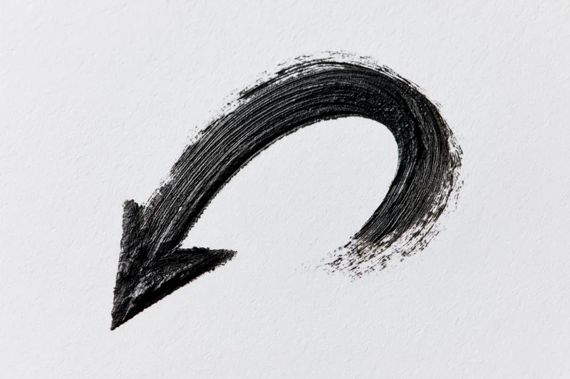 Hand-drawn curved arrow pointing downward-left on white paper