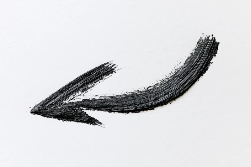 Hand-drawn curved arrow pointing downward-left on white paper