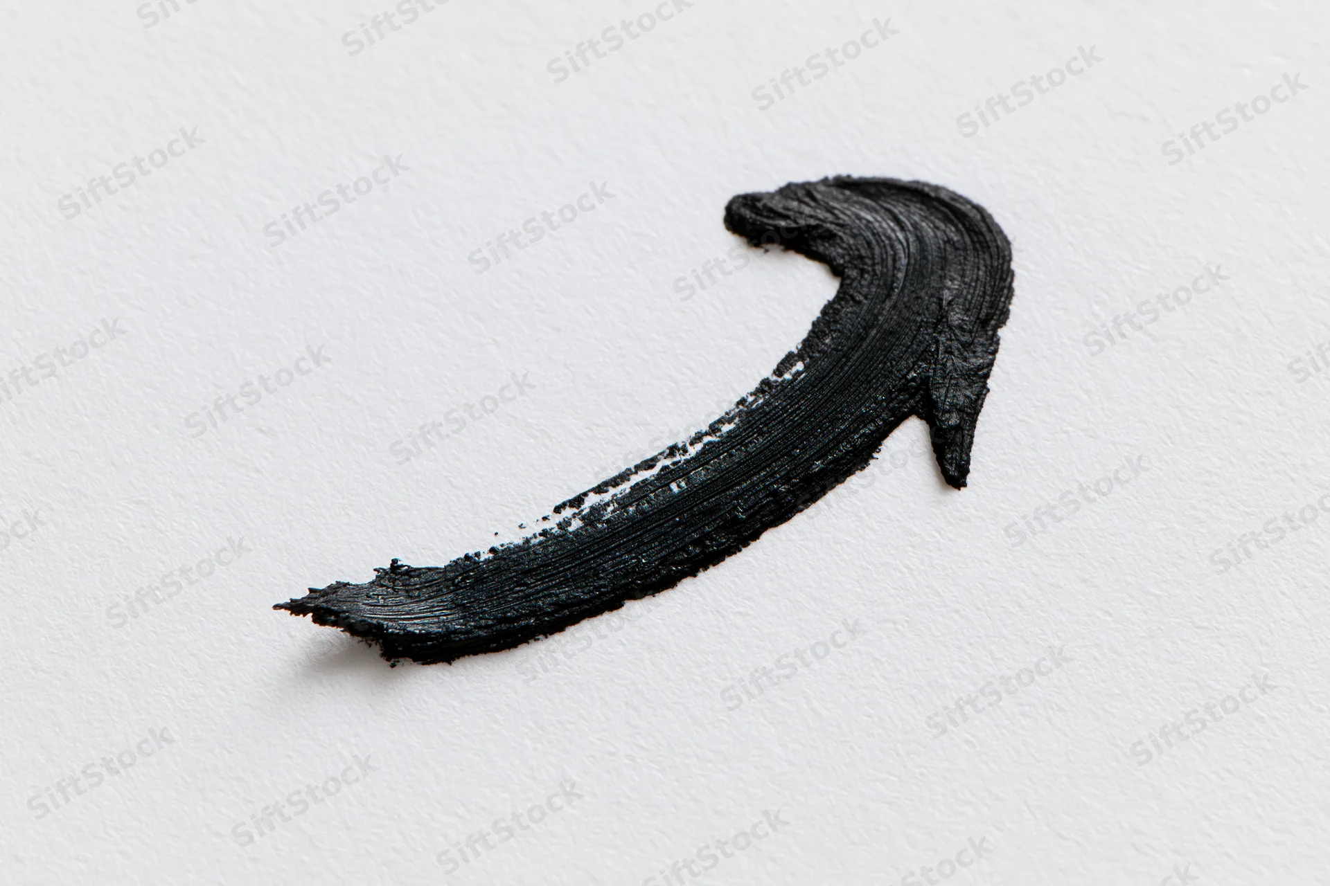 Black paint brushstroke forming a curved arrow pointing downward left on white background