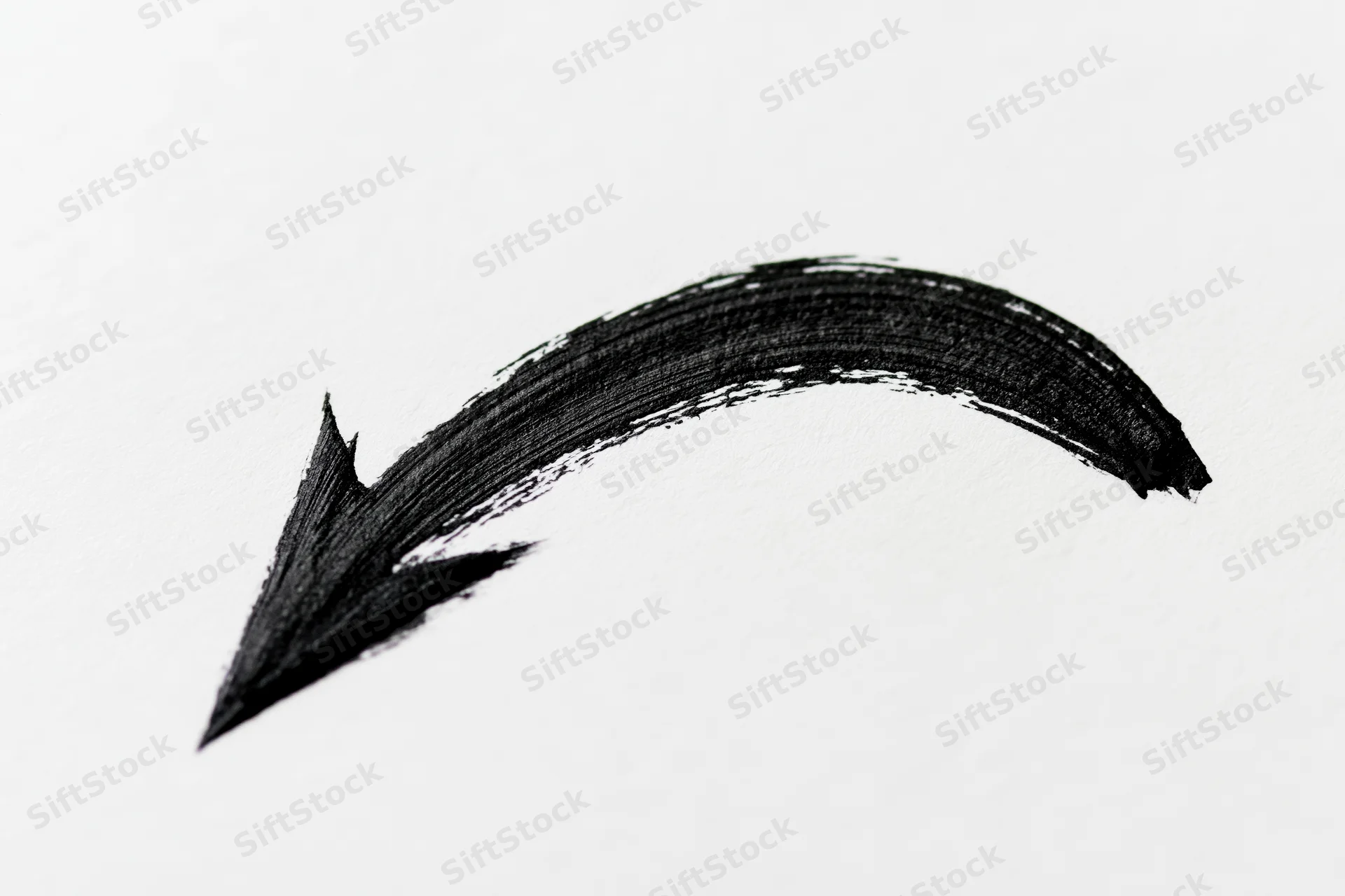 Hand-drawn black curved arrow on white paper background