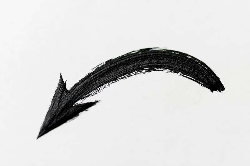Hand-drawn black curved arrow on white paper background