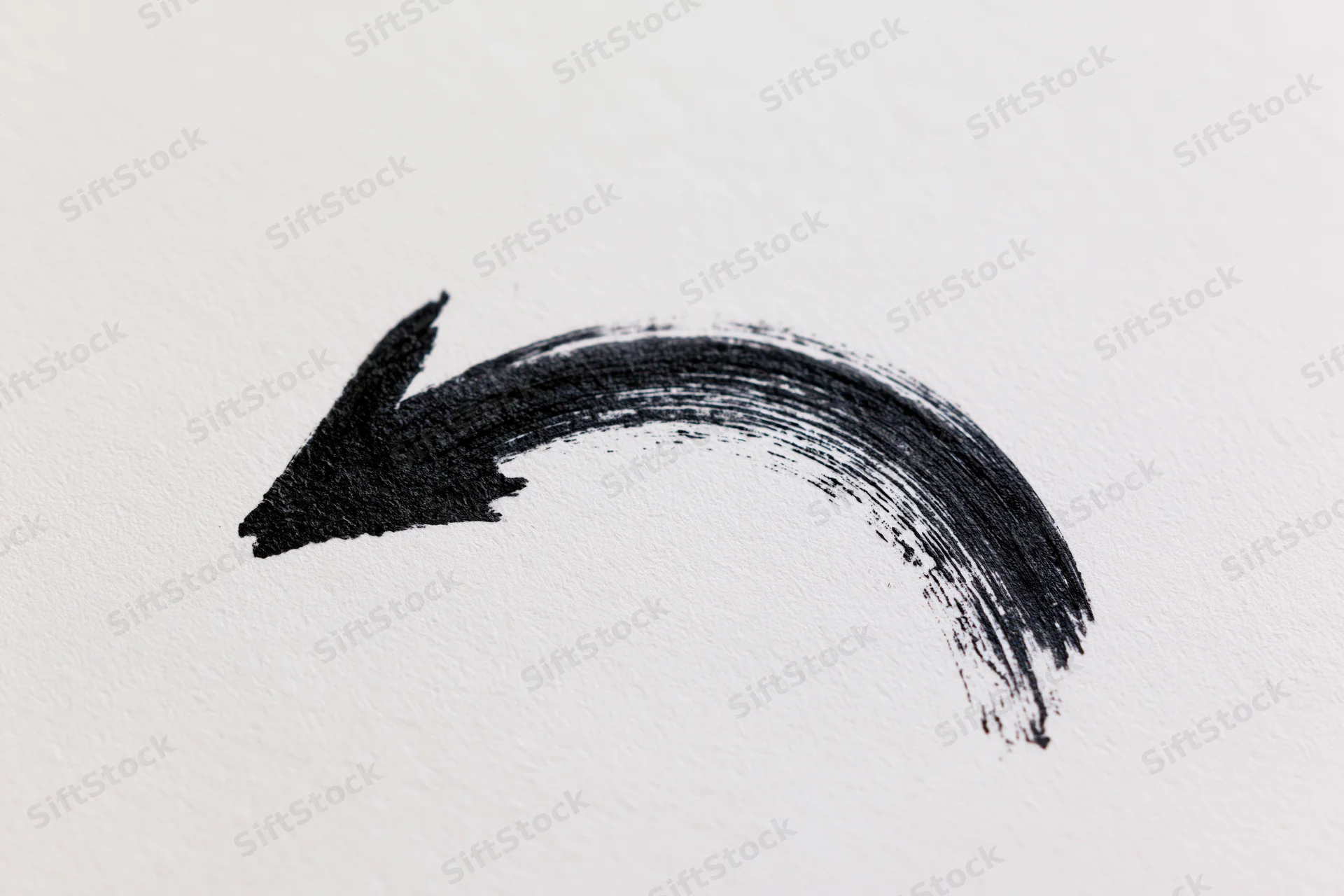 Hand-drawn black curved arrow on white paper