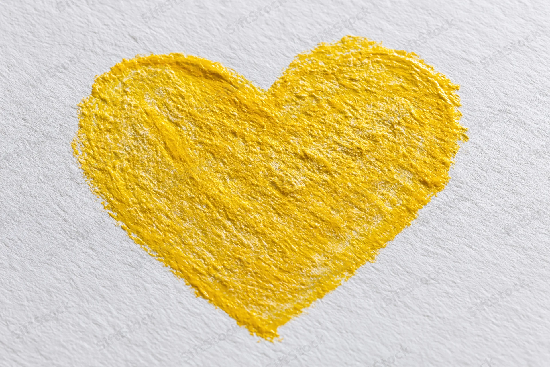 Yellow heart drawn with wax crayon on textured white paper