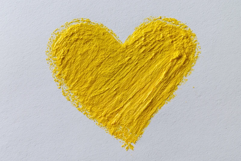 Yellow heart shape drawn with wax crayon on white paper