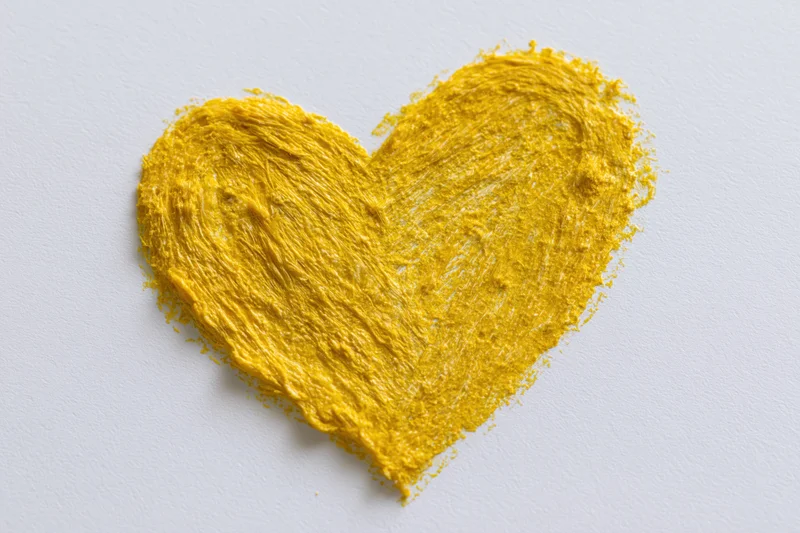 Yellow wax crayon heart drawn on white paper