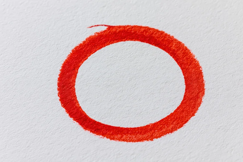 Hand-drawn red marker circle on white paper