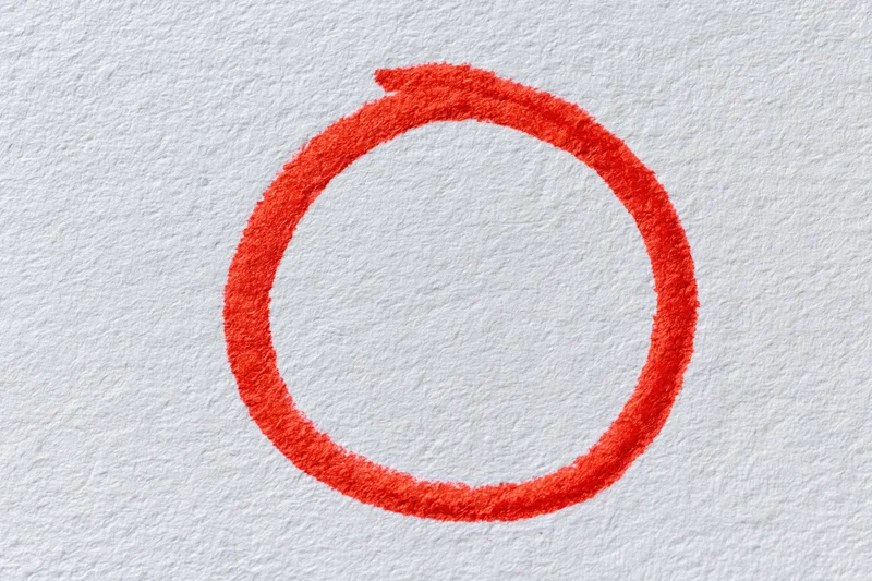 Hand-drawn red marker circle on white textured paper