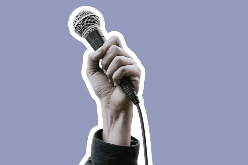 Hand gripping a wired microphone raised upward against a lavender background
