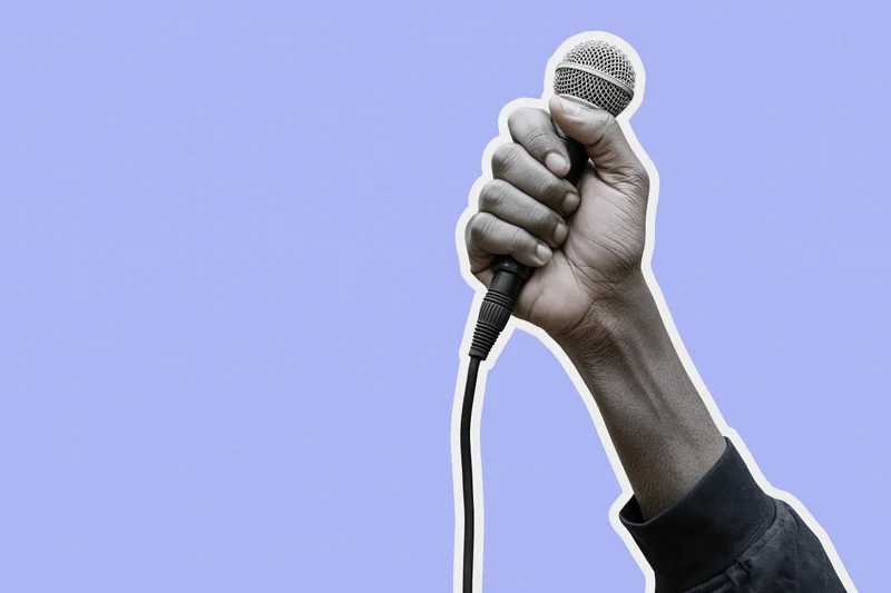 Hand gripping a wired microphone raised upward against a purple background