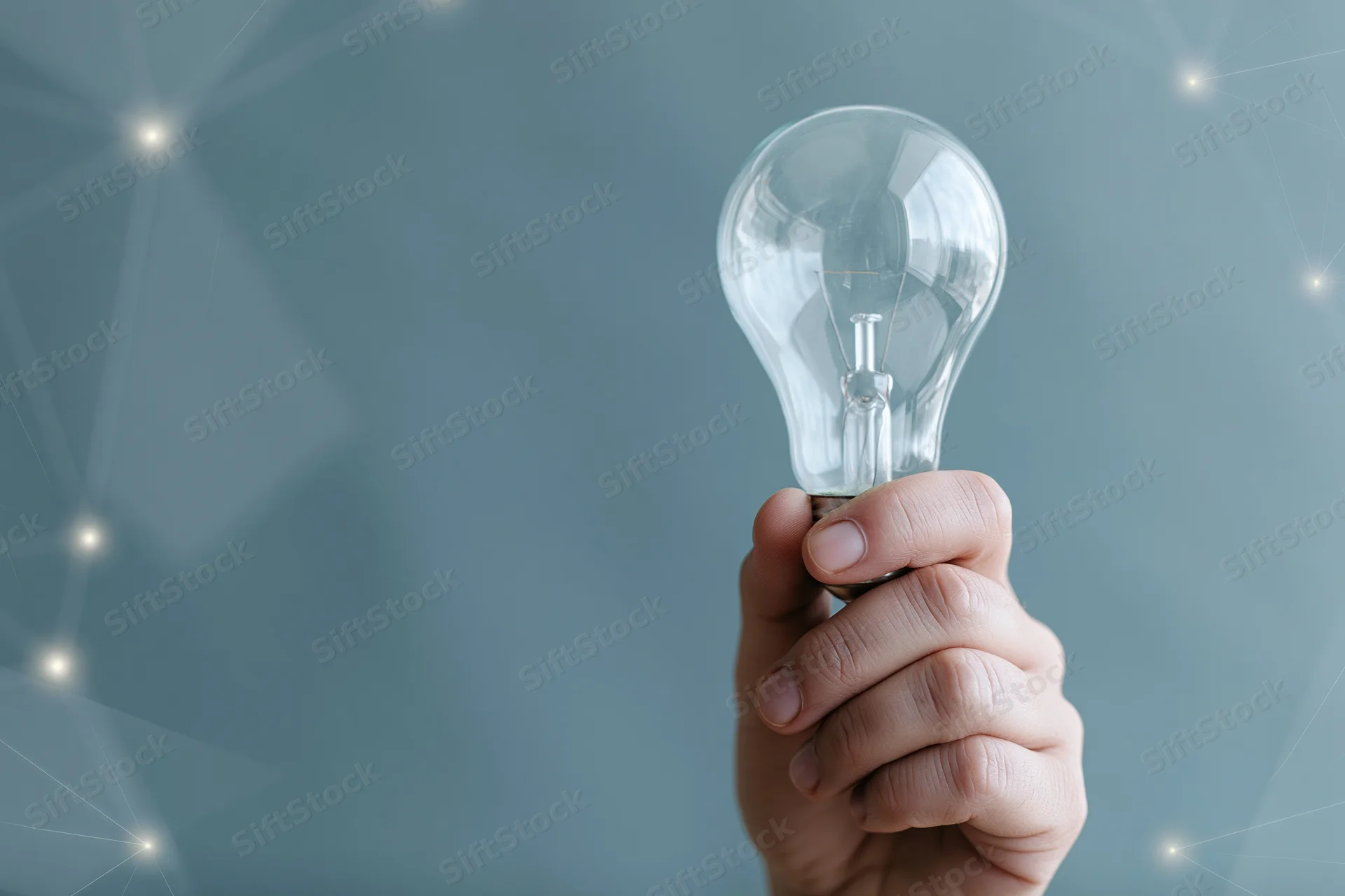 Hand holding a clear glass incandescent light bulb against a digital network background
