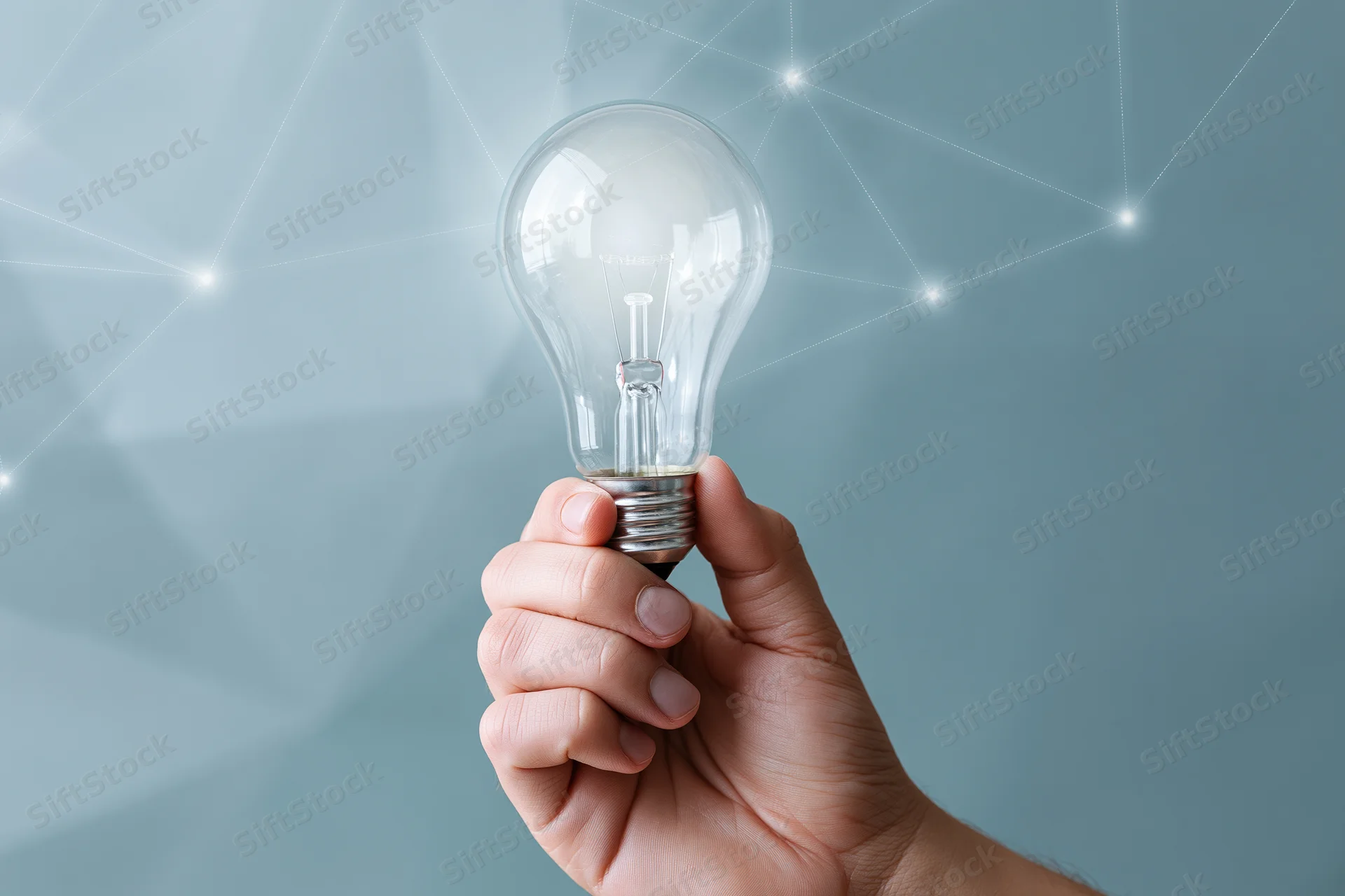 Hand holding a clear glass incandescent light bulb against a blue digital network background