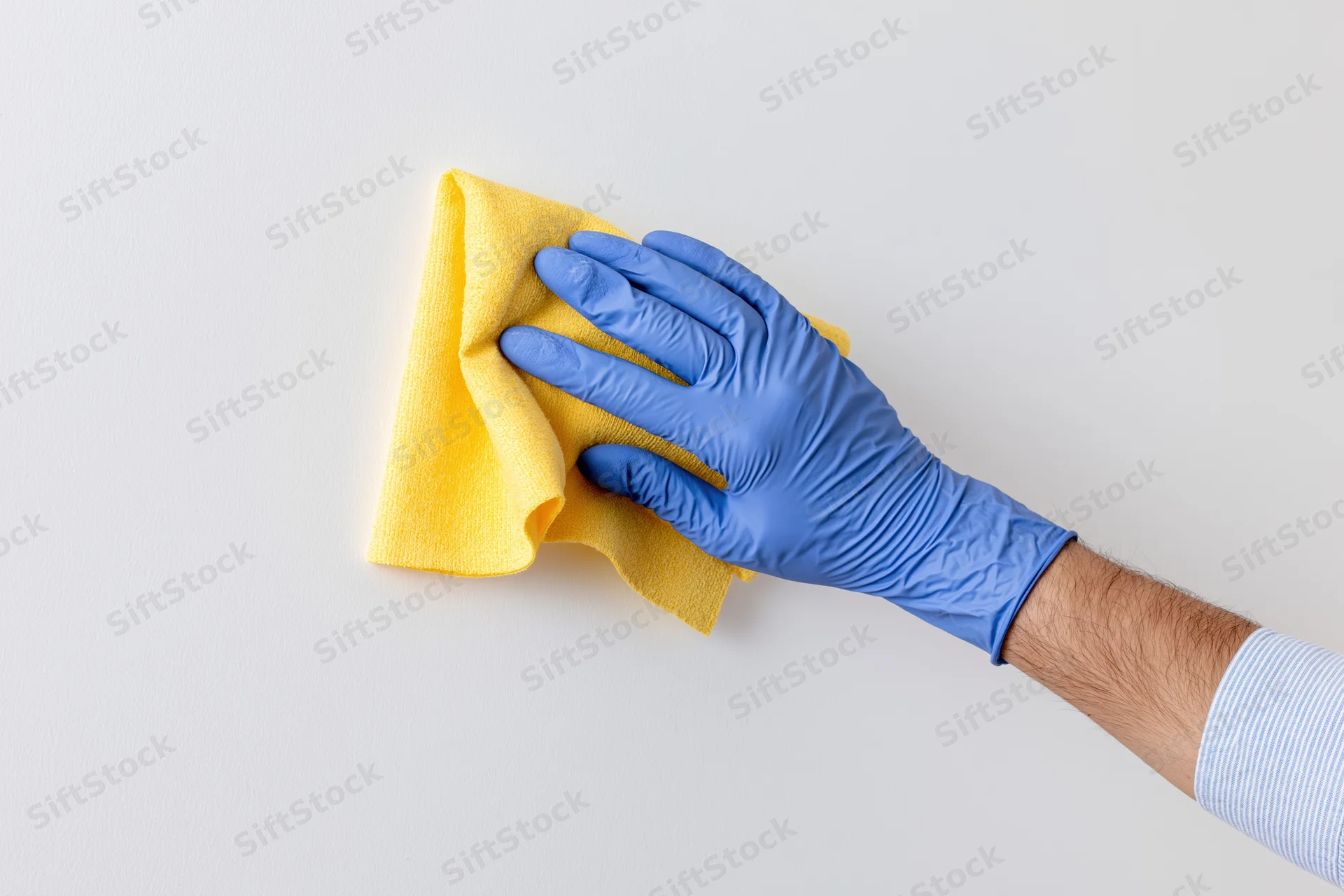 Hand in blue latex glove wiping white surface with yellow cloth