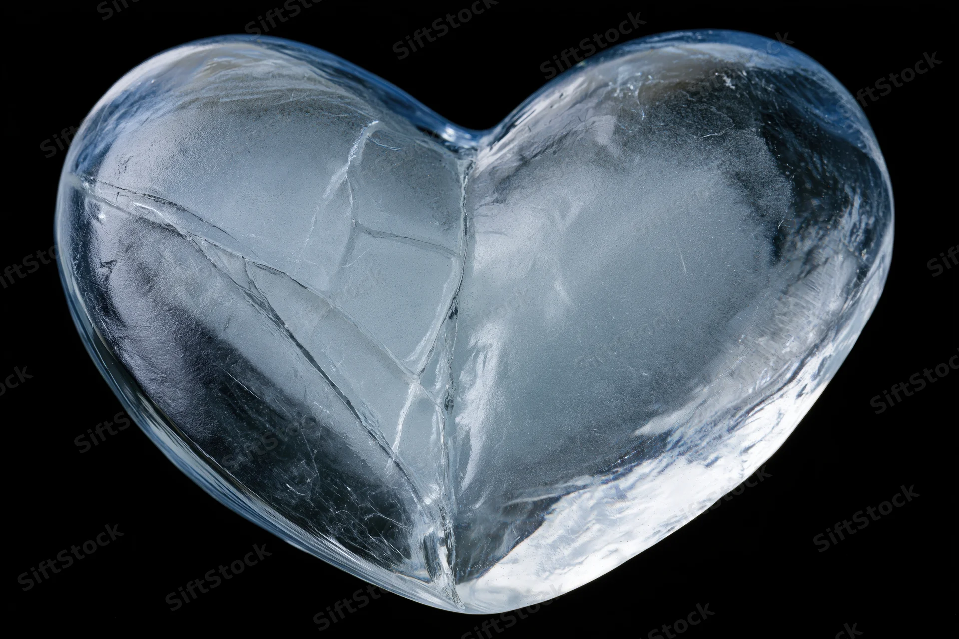Heart-shaped ice block with cracks and frost on black background