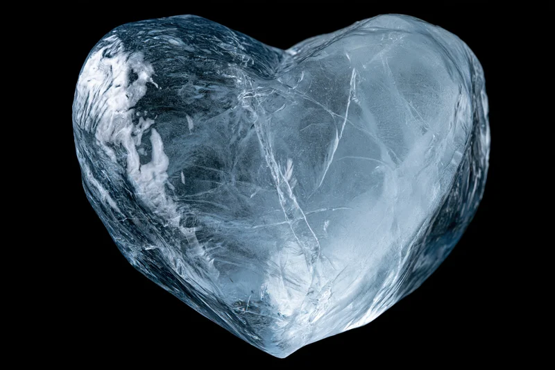 Heart-shaped block of clear ice centered against a pure black background