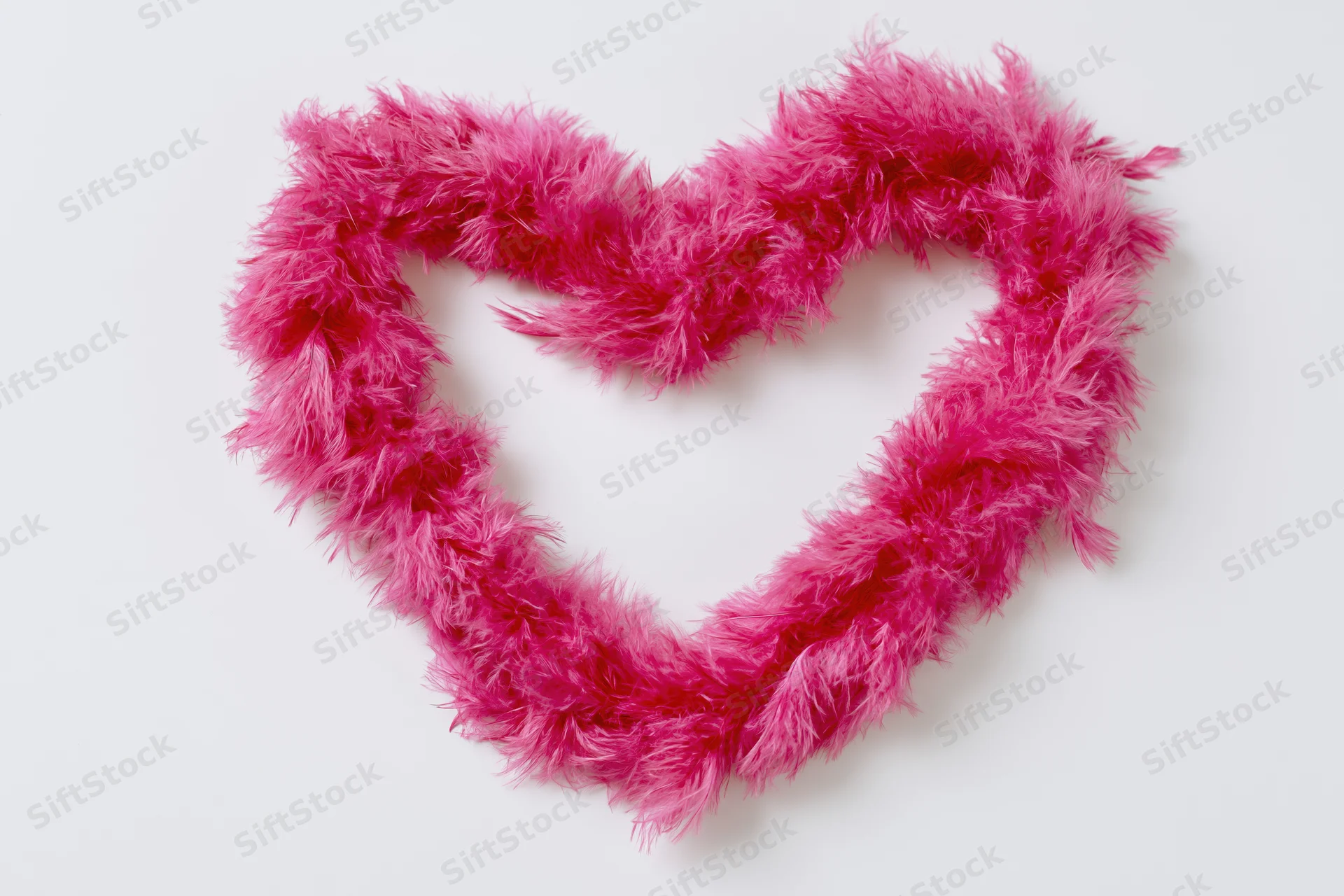 Heart-shaped feather boa arranged on white background