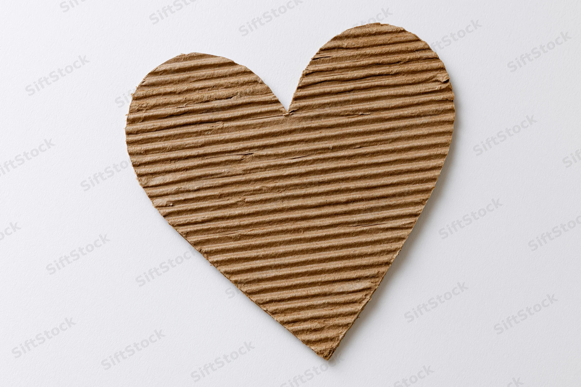 Heart-shaped corrugated kraft cardboard cutout on white background