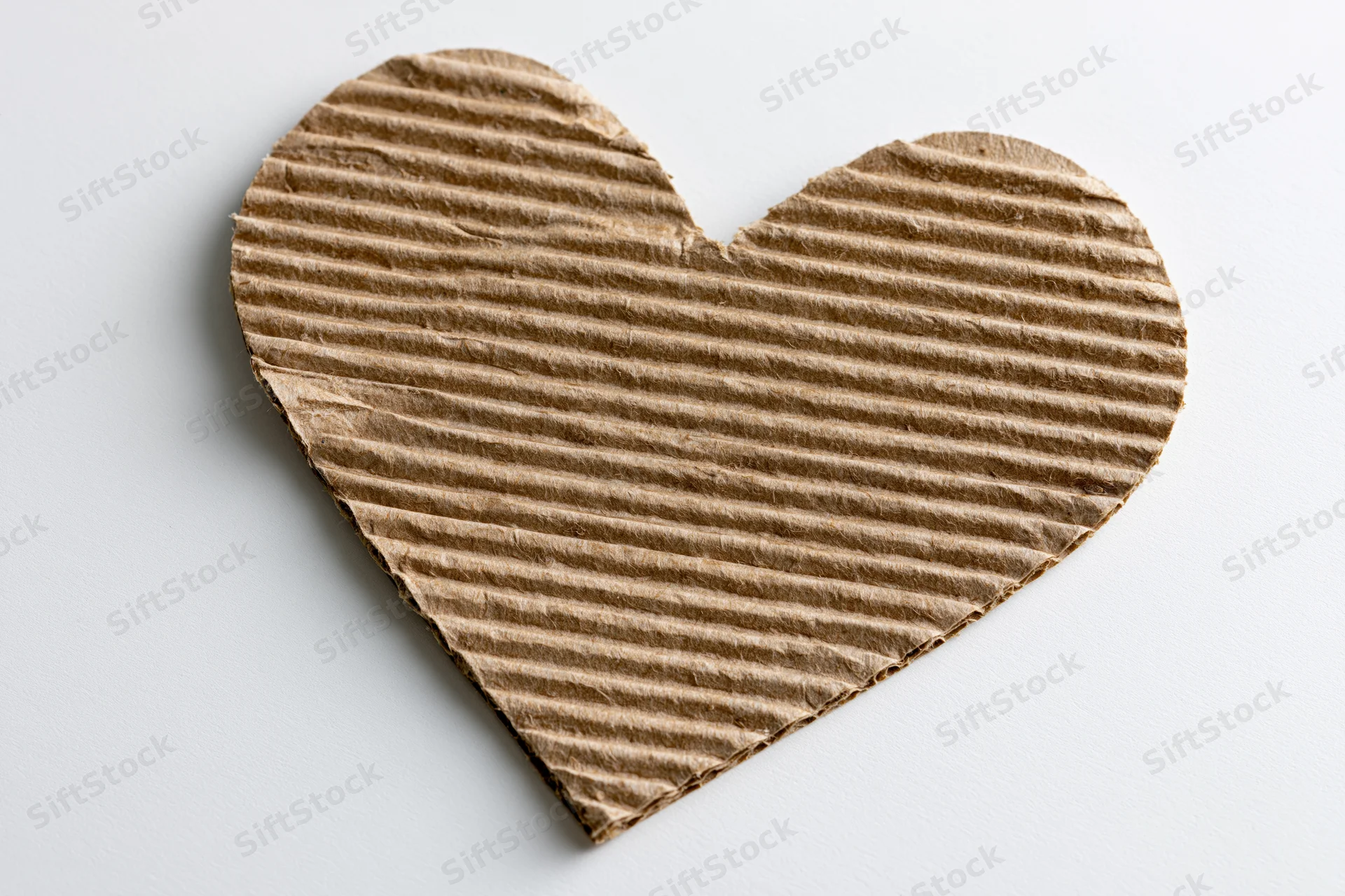 Heart-shaped corrugated kraft cardboard cutout on white background
