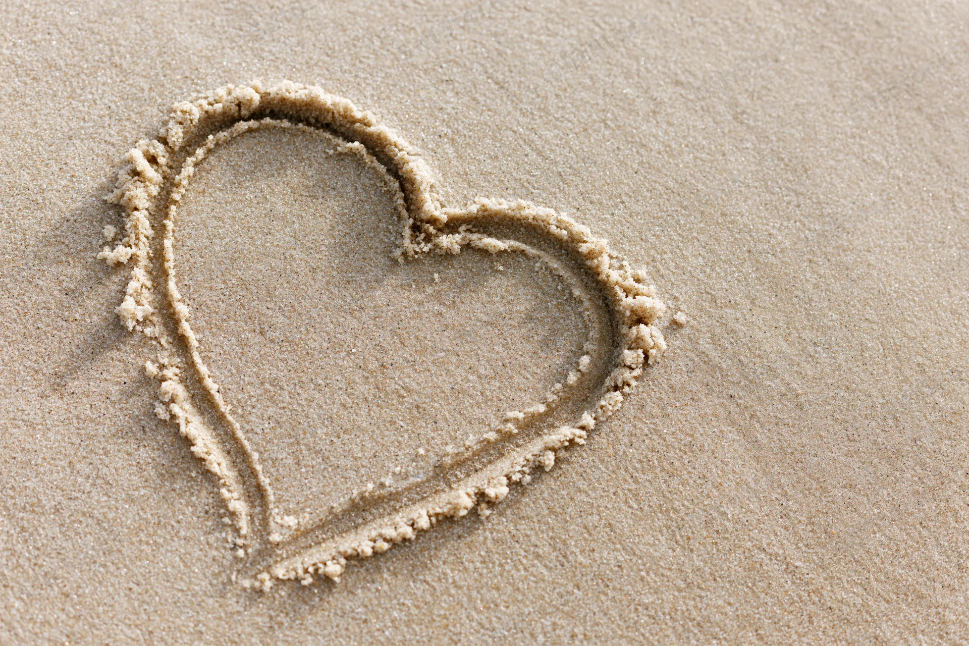 Heart shape drawn in wet sand on a beach