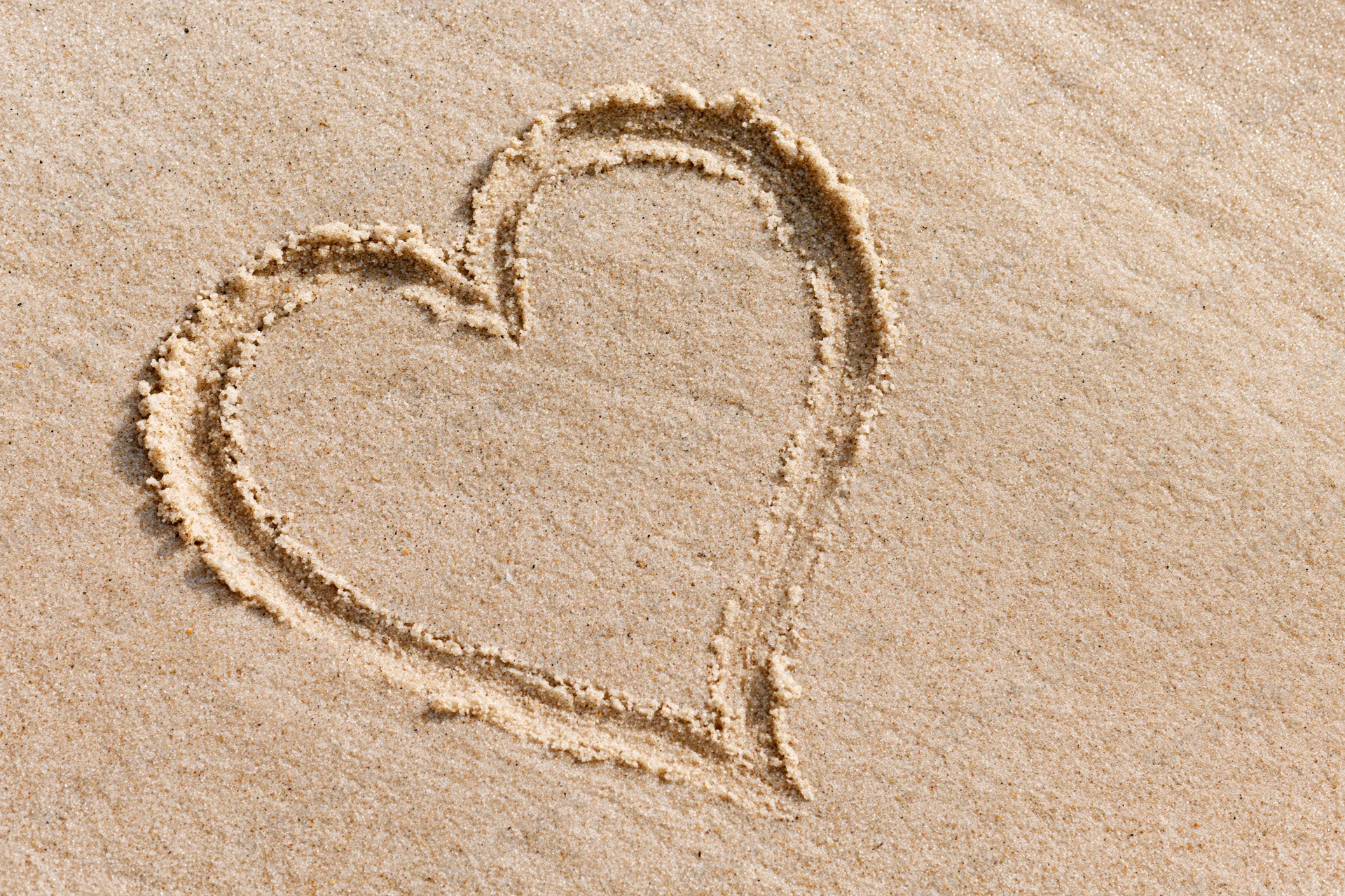 Heart shape drawn in wet sand on a beach