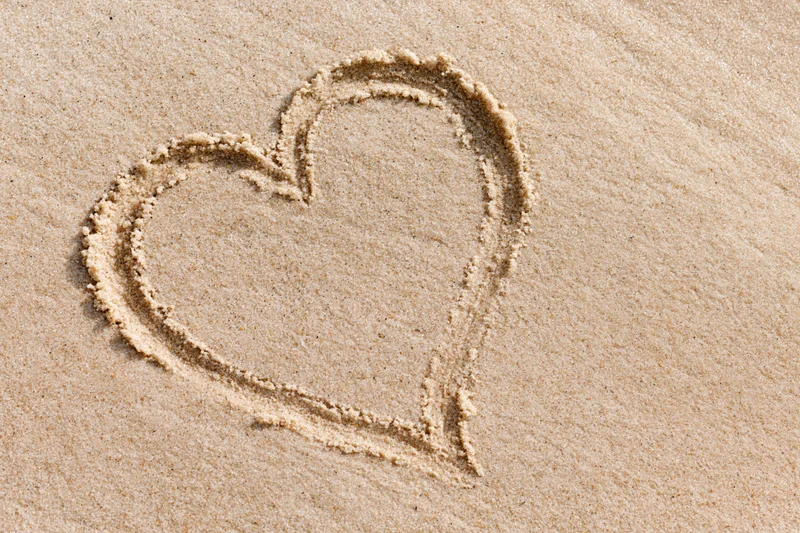 Heart shape drawn in wet sand on a beach