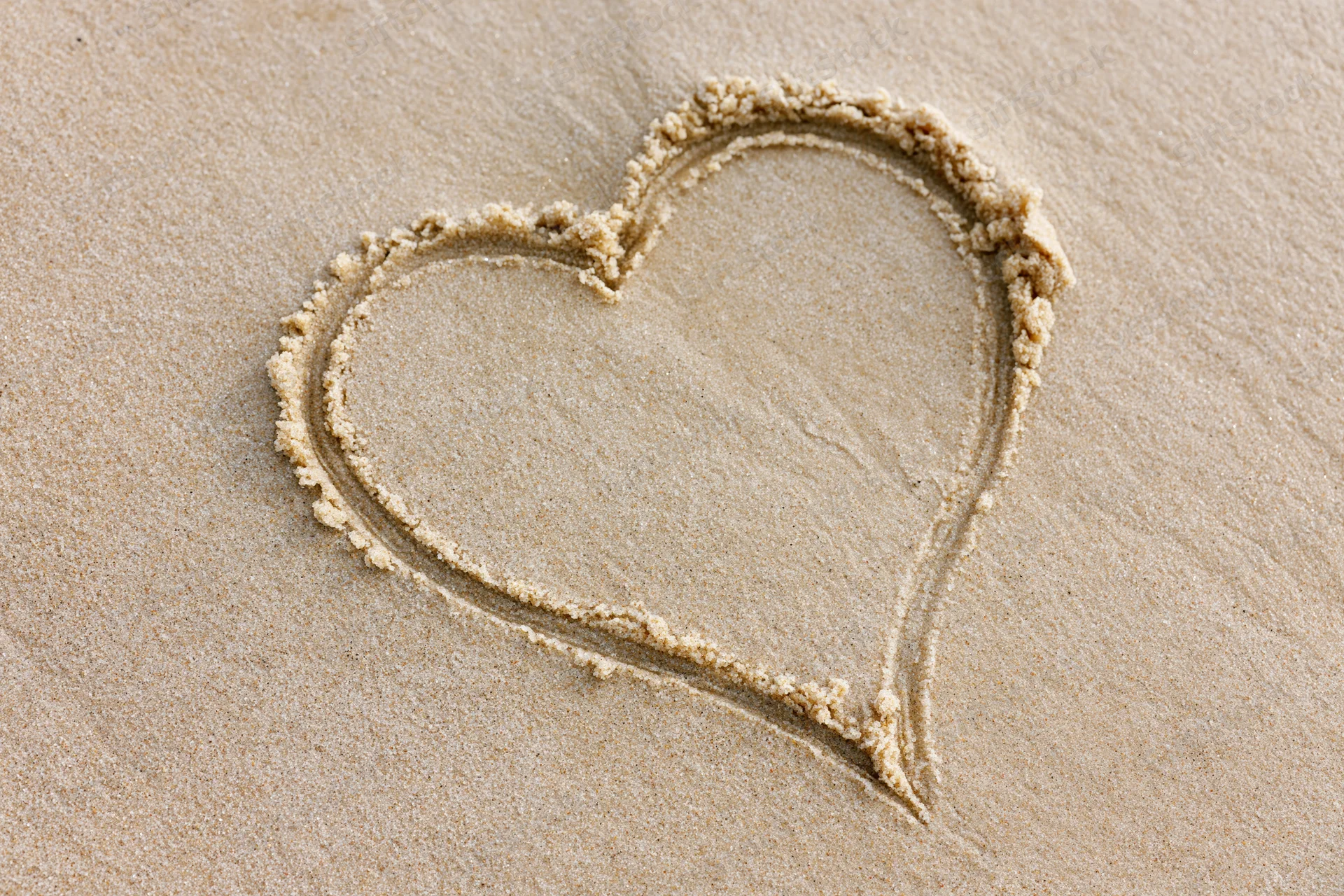 Heart shape drawn in wet sand on a beach