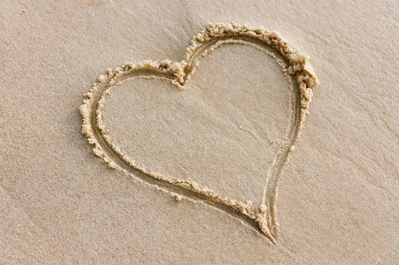 Heart shape drawn in wet sand on a beach