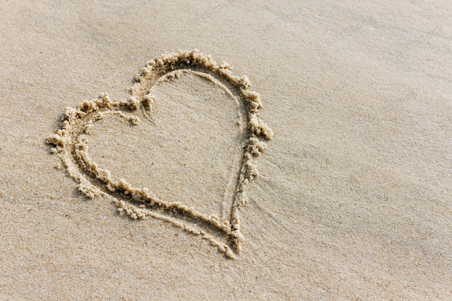 Heart shape drawn in wet sand on a beach