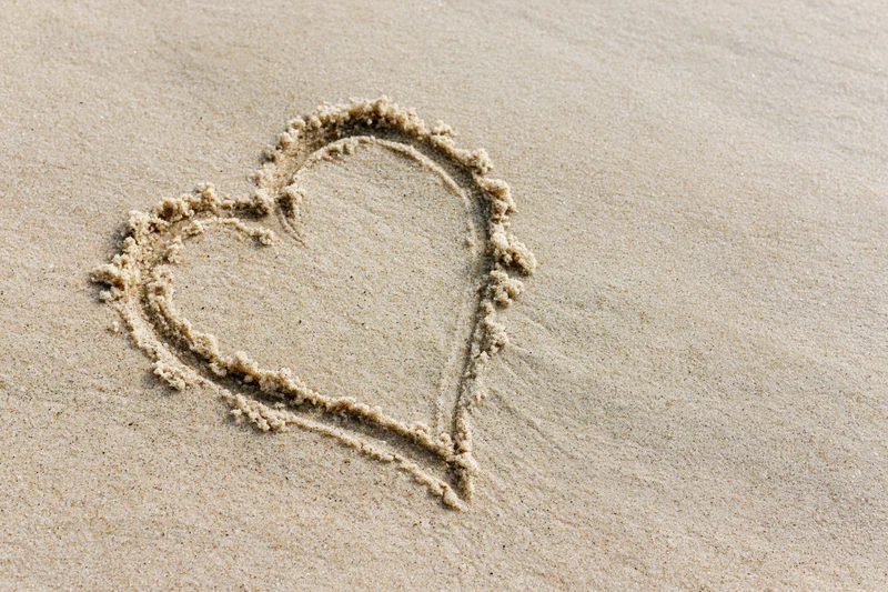 Heart shape drawn in wet sand on a beach