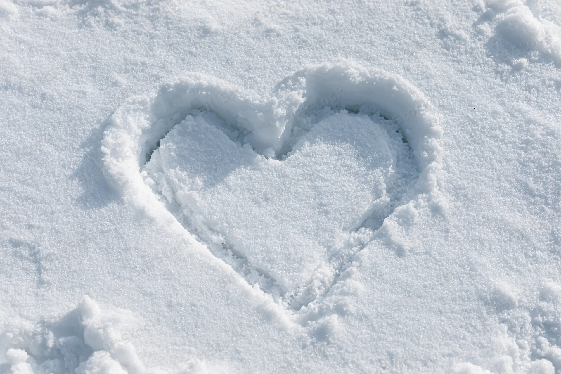 Heart shape drawn in fresh snow on a flat snowy surface