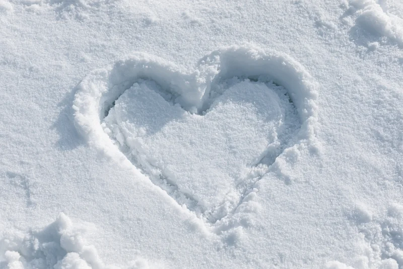 Heart shape drawn in fresh snow on a flat snowy surface