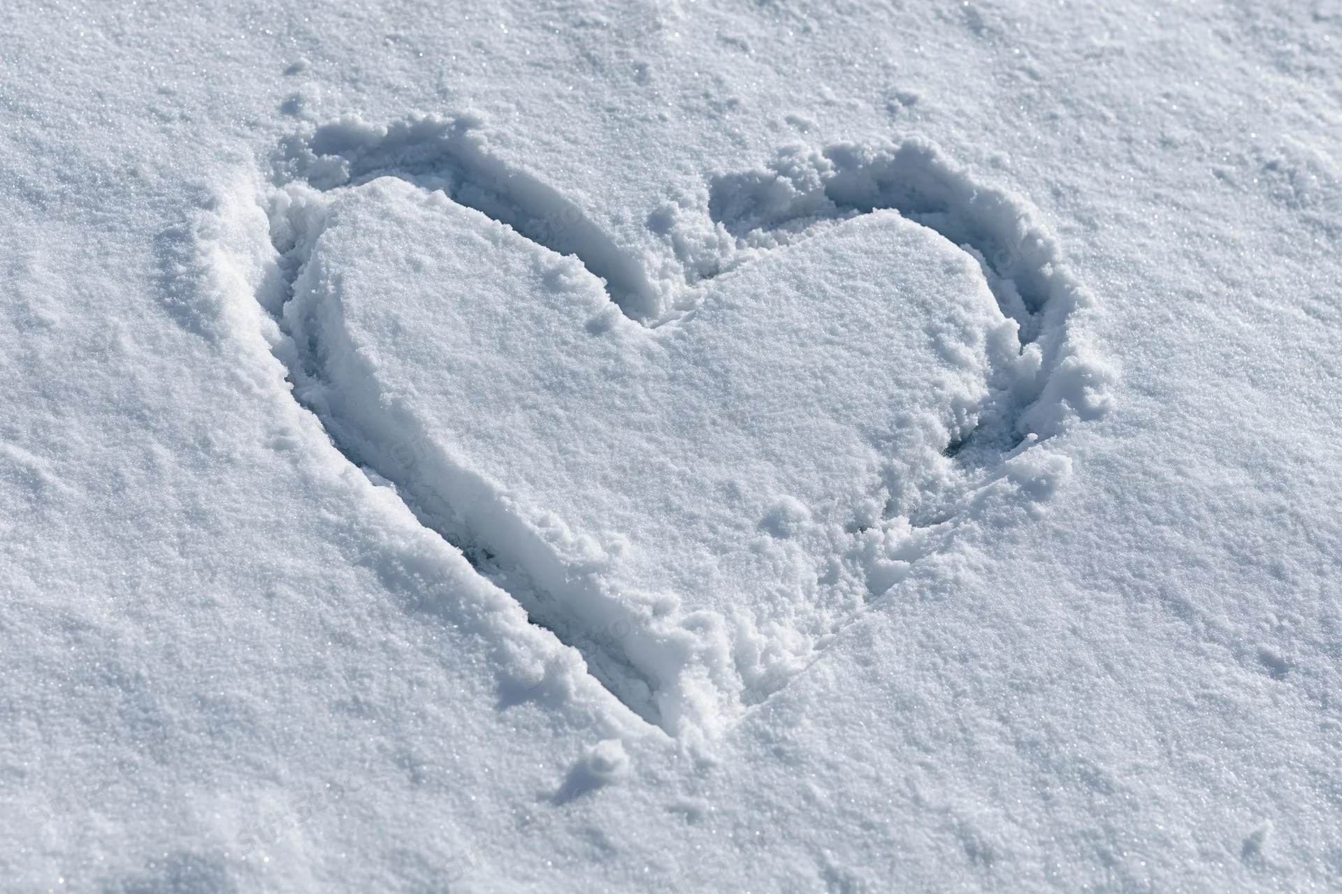 Heart shape drawn in fresh snow on a flat outdoor surface