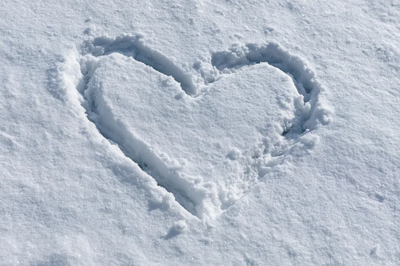 Heart shape drawn in fresh snow on a flat outdoor surface