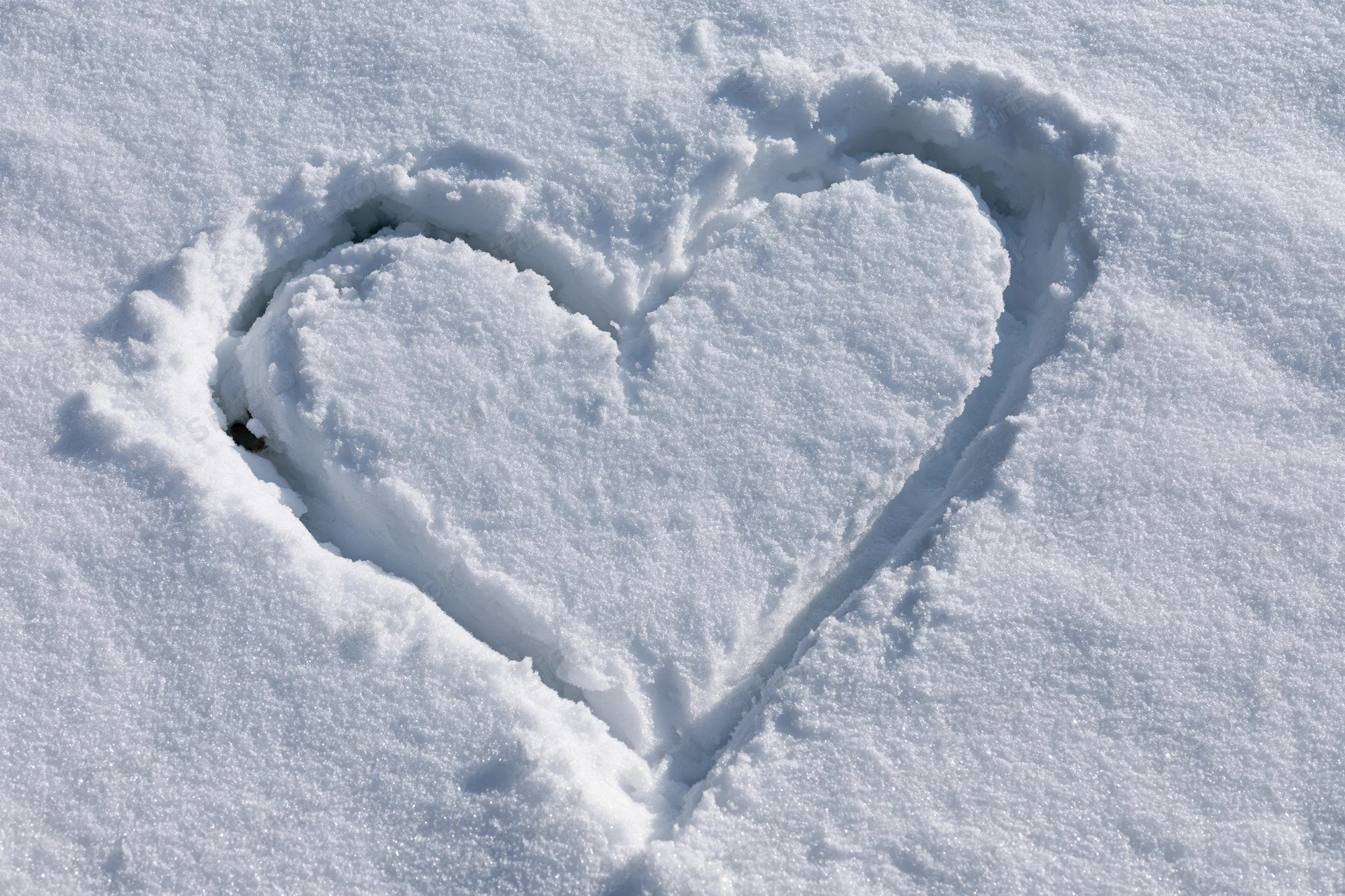 Heart shape drawn in fresh snow on a flat outdoor surface