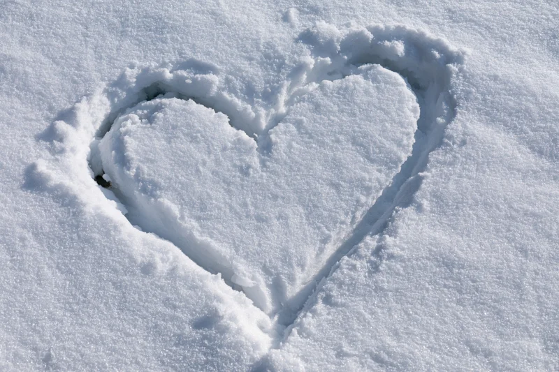 Heart shape drawn in fresh snow on a flat outdoor surface