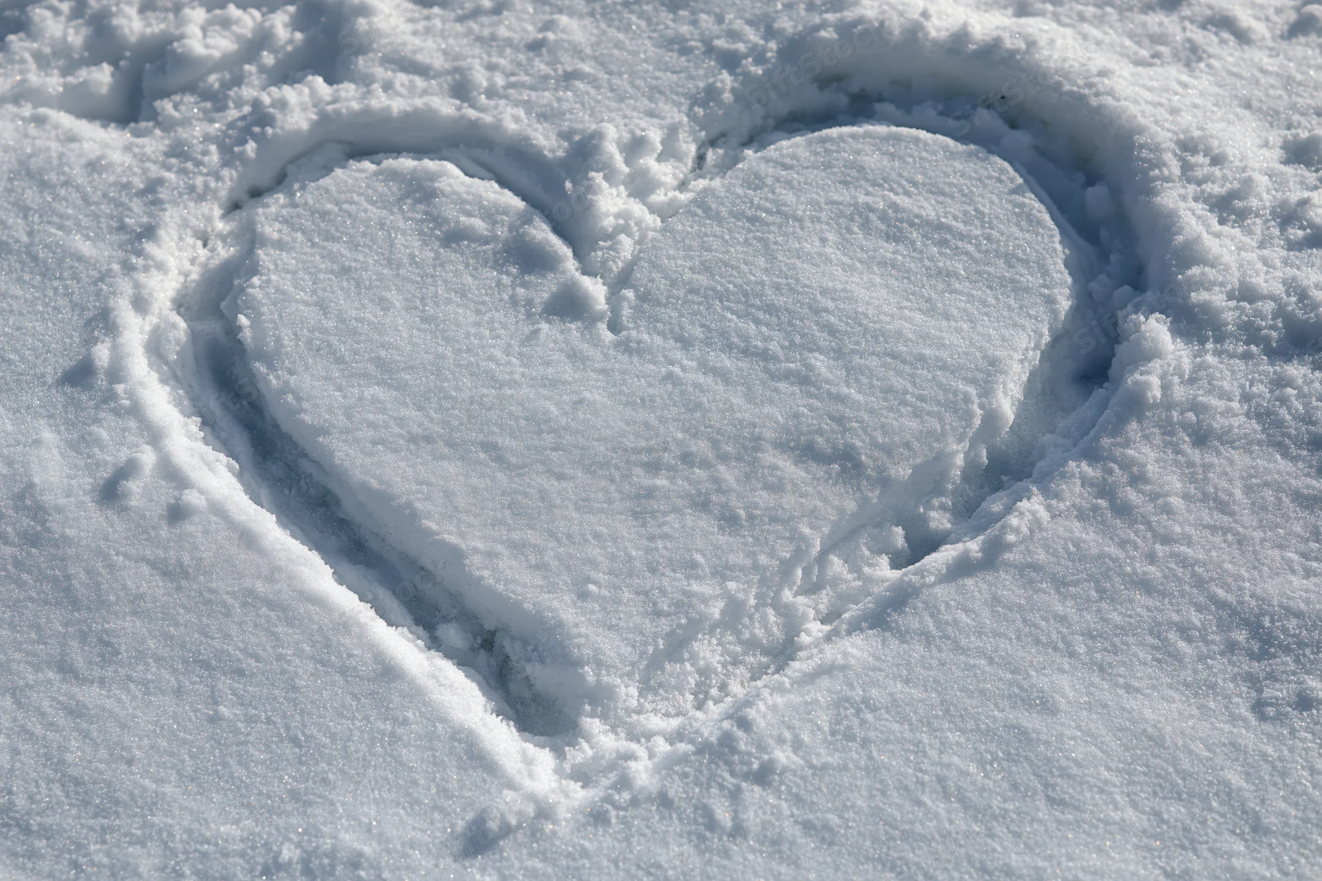 Heart shape drawn in fresh snow on a flat outdoor surface
