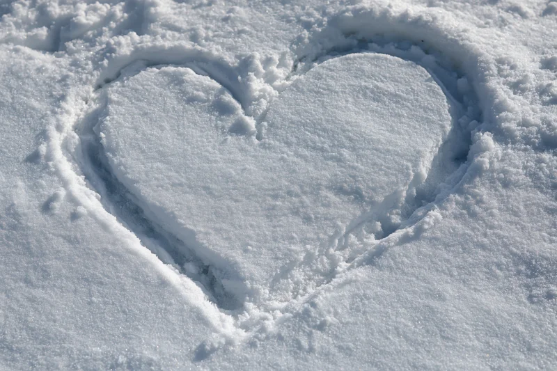 Heart shape drawn in fresh snow on a flat outdoor surface