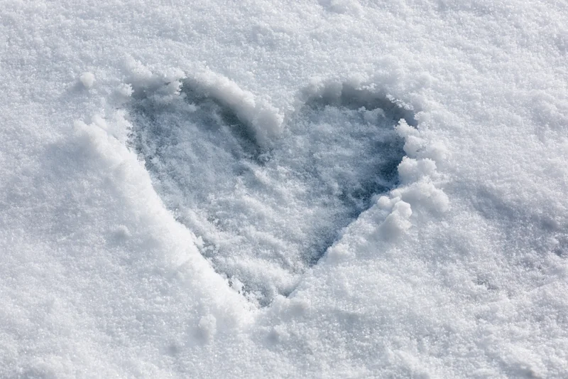 Heart shape drawn in fresh snow on a flat outdoor surface