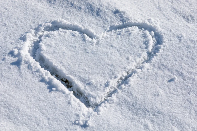 Heart shape drawn in fresh snow on a flat ground surface
