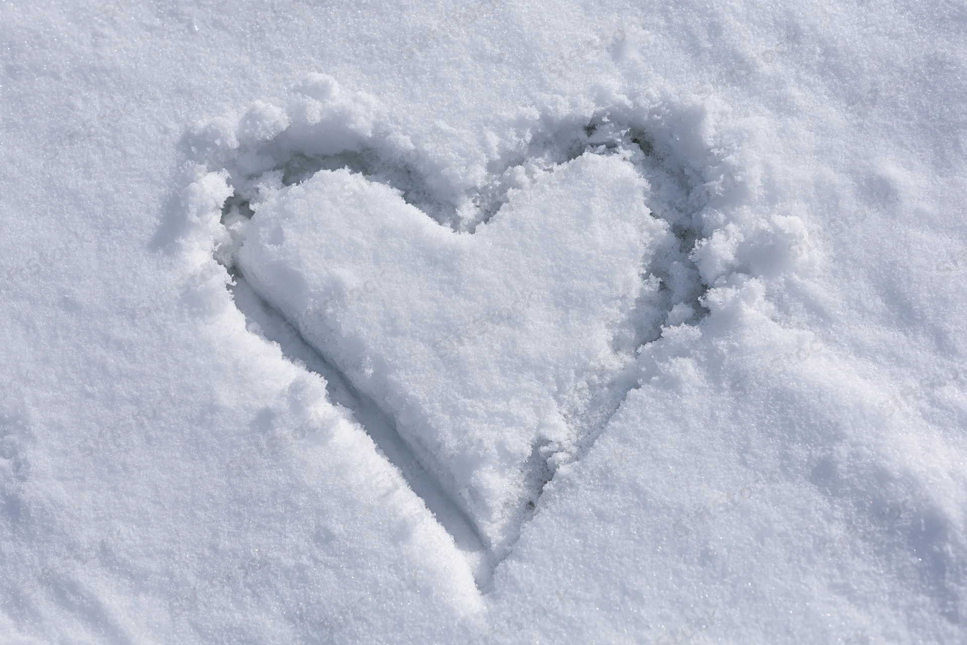 Heart shape drawn in fresh snow on a flat surface
