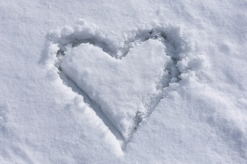 Heart shape drawn in fresh snow on a flat surface