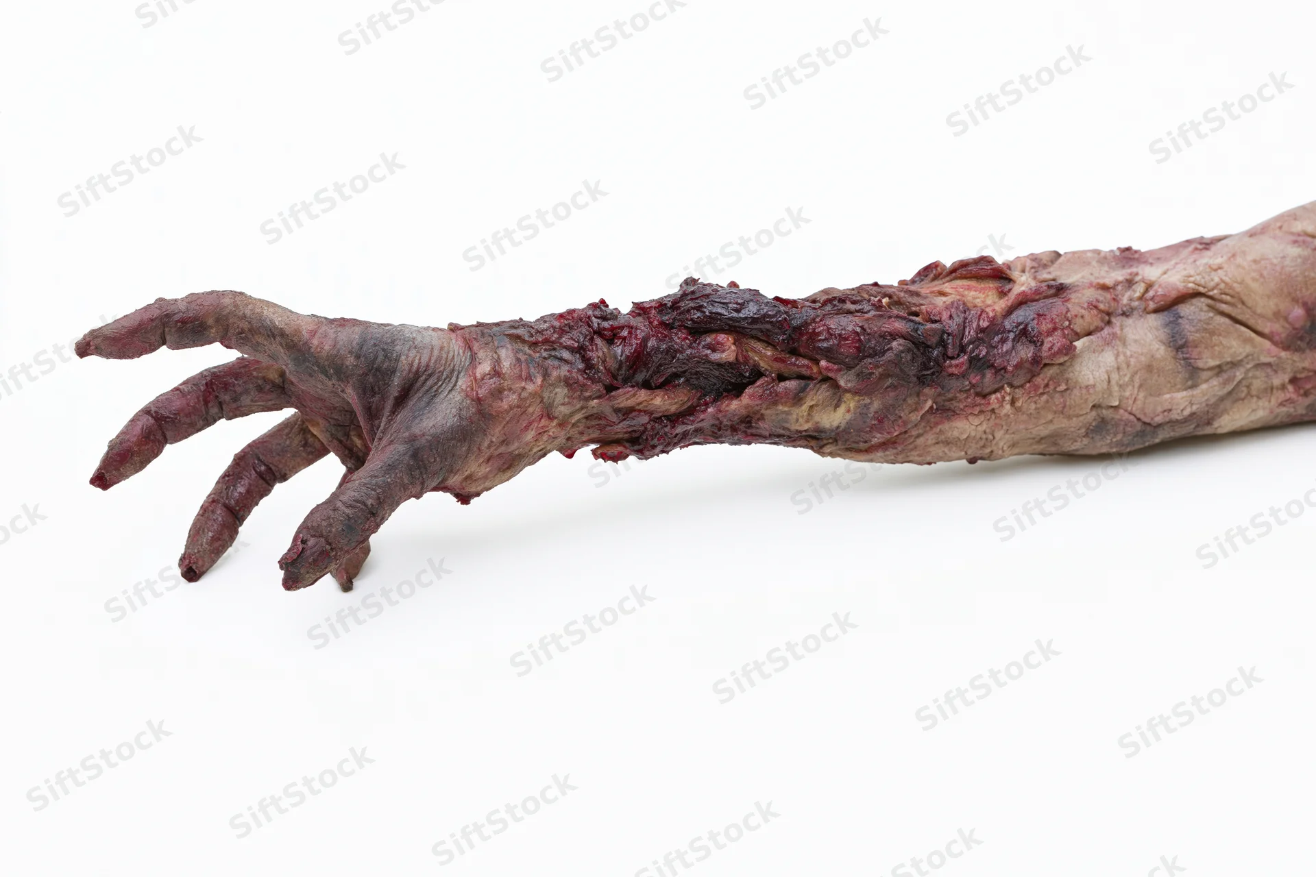 Zombie hand with prosthetic makeup and decayed flesh on white background