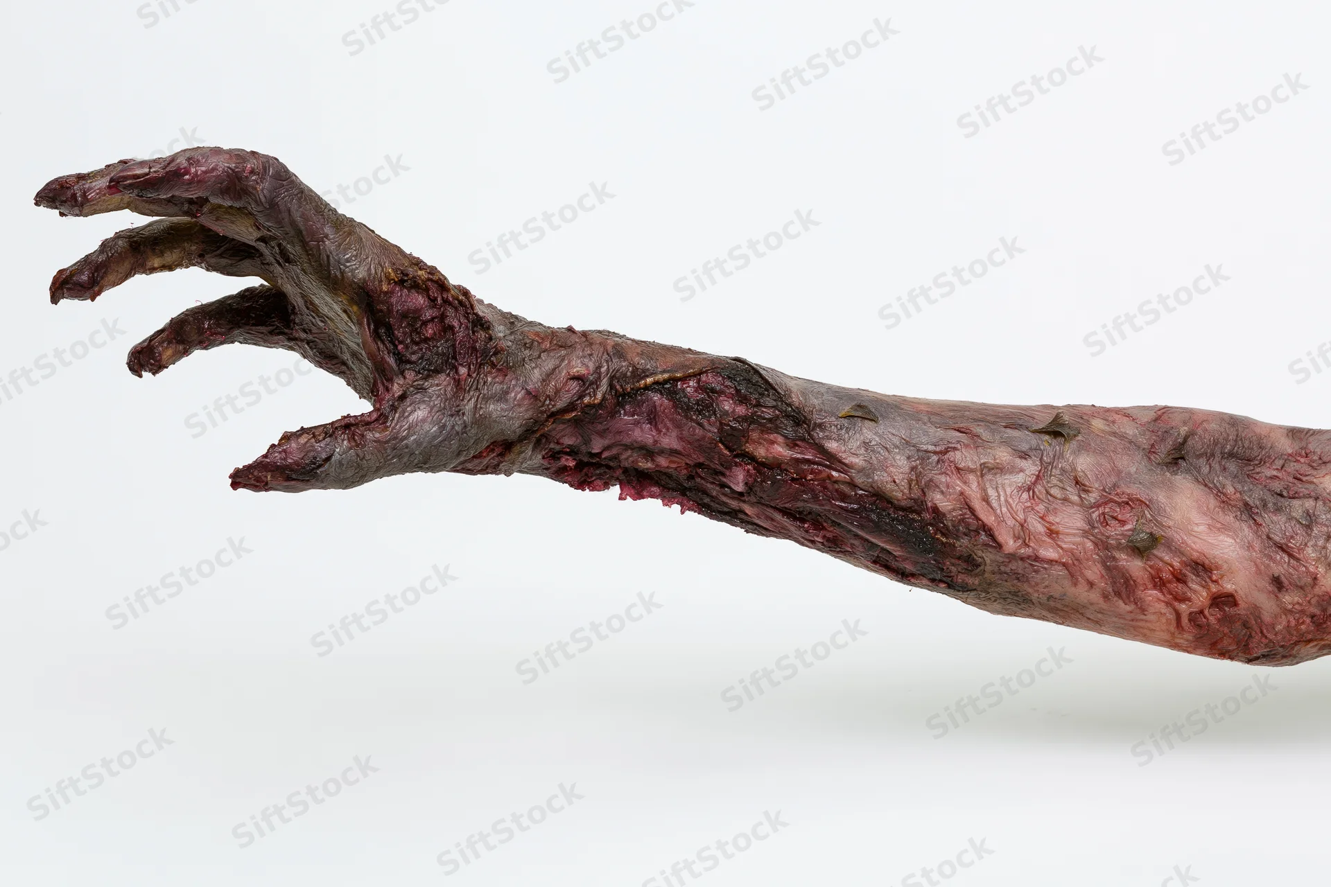 Zombie hand with prosthetic makeup and decayed skin isolated on white background
