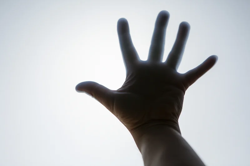 Hand pressed against frosted glass with light shining through
