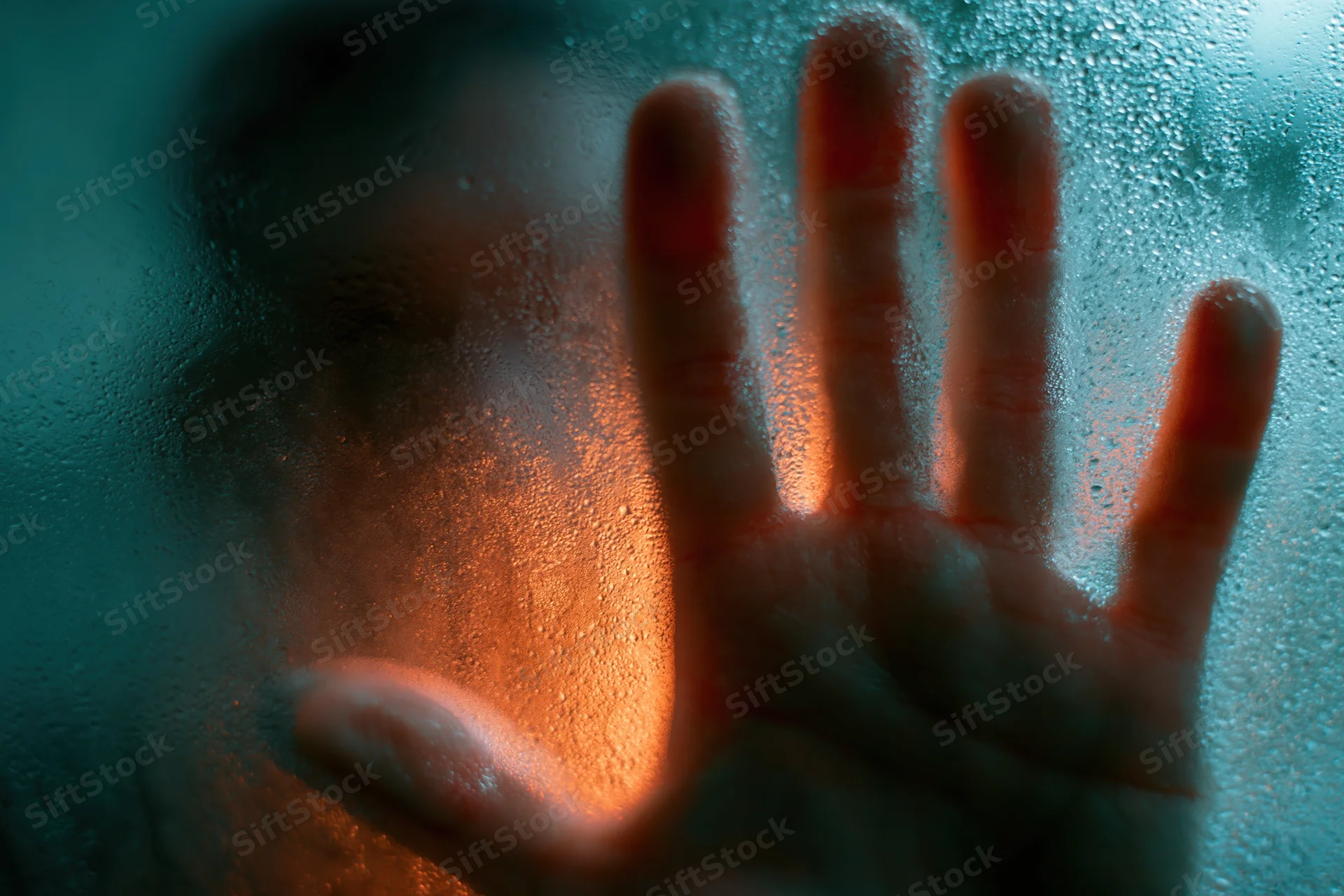 Hand pressed against fogged glass in a steamy bathroom