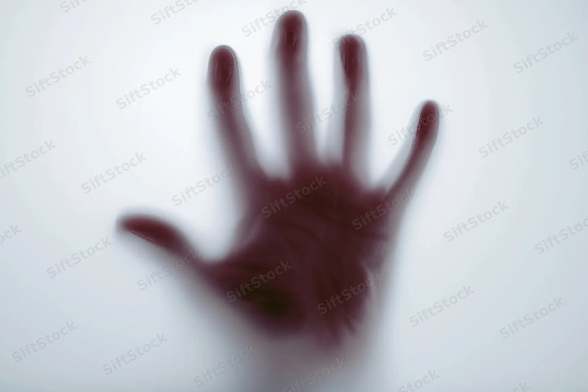 Blurred hand pressed against frosted glass surface