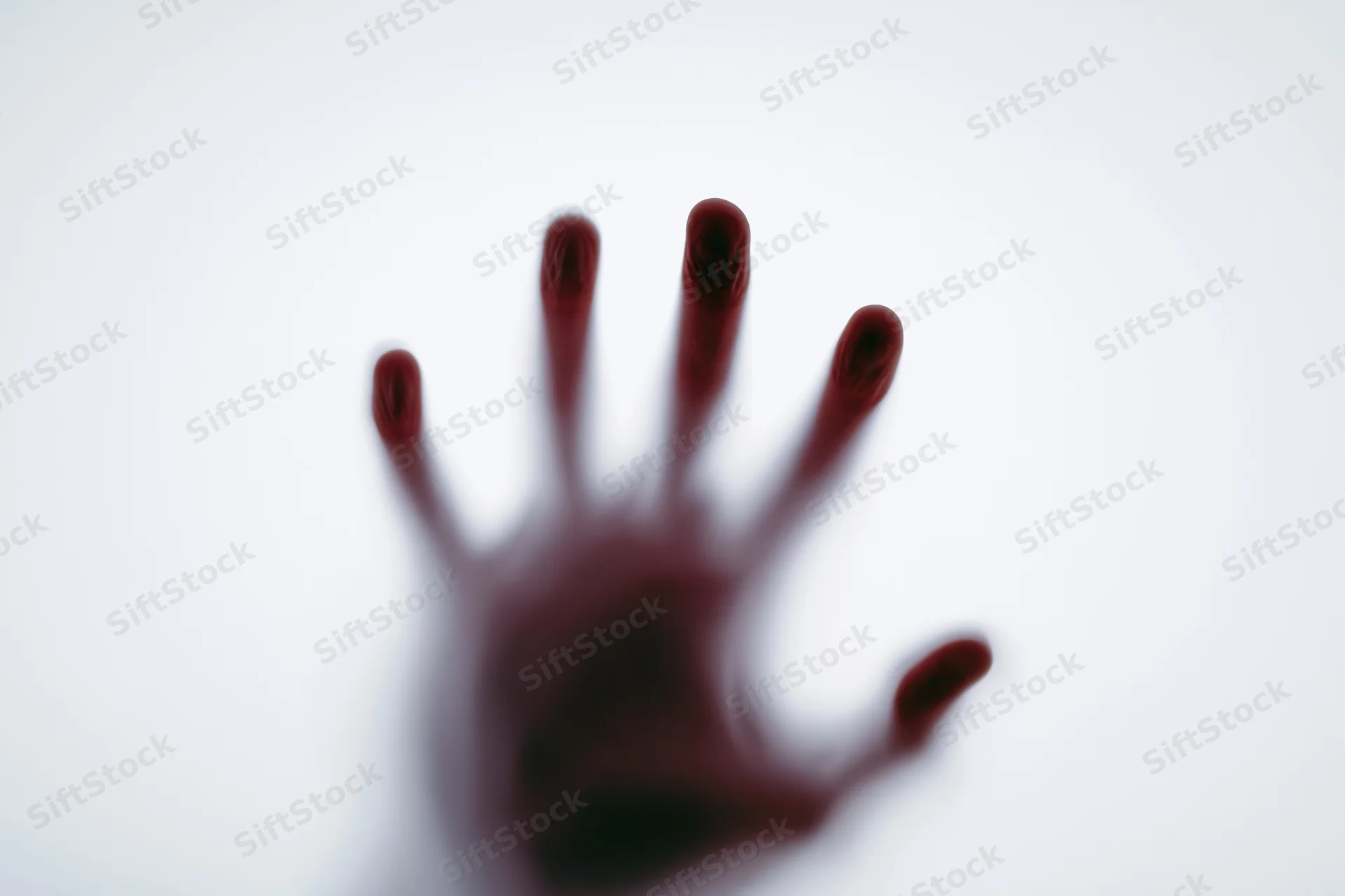Blurred red hand pressed against frosted glass surface